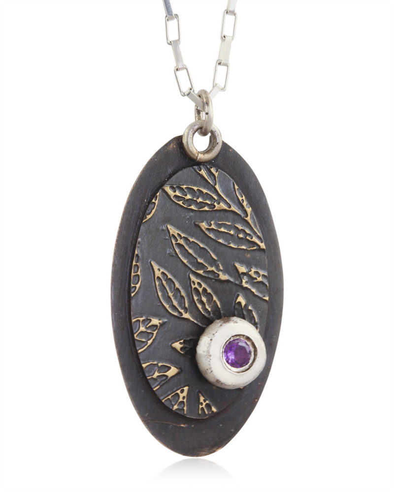 Decorative pendant with intricate leaf designs and a purple amethyst gemstone on a white background