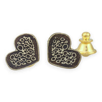 Heart-shaped metal pin with intricate designs on a white background