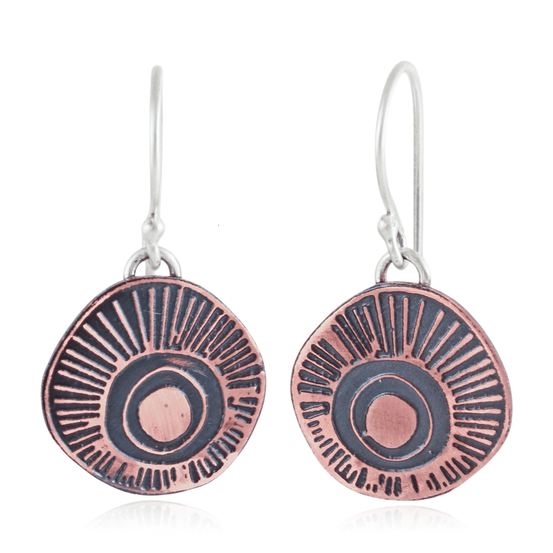 Copper and silver earrings with circular ray design on a white background