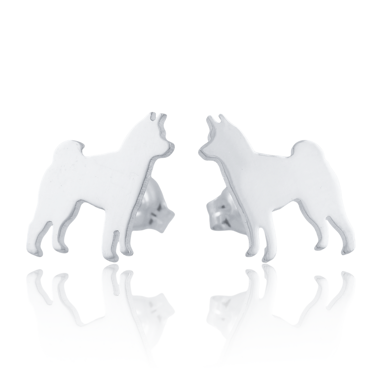 A pair of silver stud earrings shaped like standing Shiba Inu dogs, shown on a white background with a soft reflection below.
