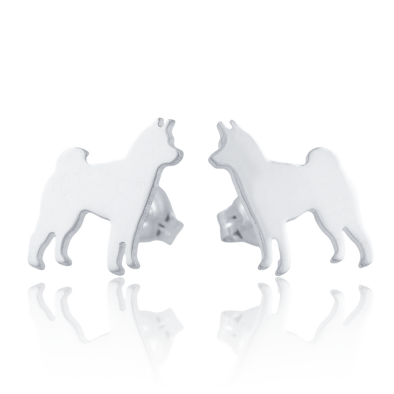 A pair of silver stud earrings shaped like standing Shiba Inu dogs, shown on a white background with a soft reflection below.