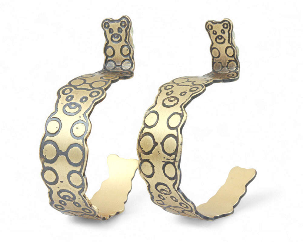 Gold hoop earrings with a interlocked teddy bear pattern on a white background
