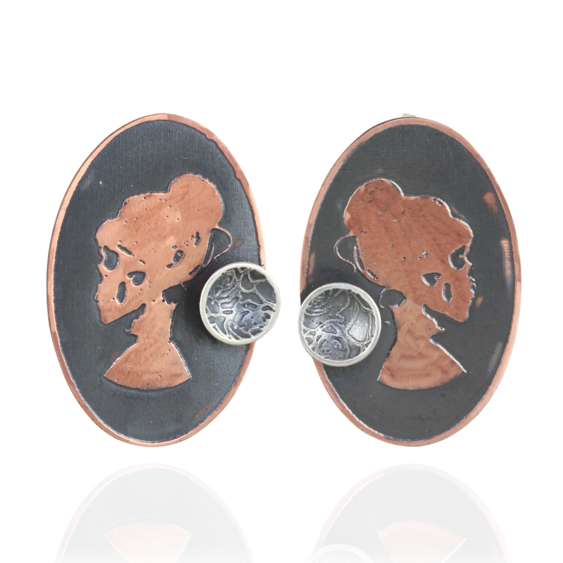 Oval pair of earrings with copper skull silhouette with a mini silver cup design  on a white background.