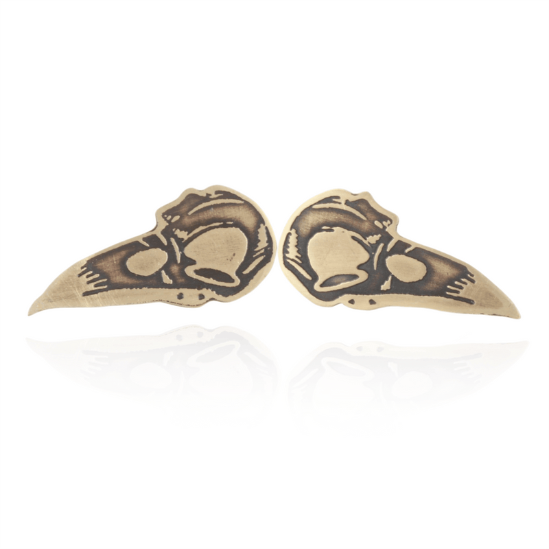 Pair of gold bird skull earrings on a white background