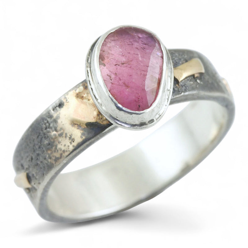 Silver ring with gold and a pink stone on a white background