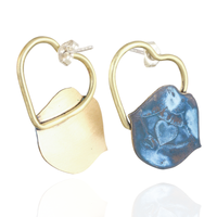 Pair of gold hoop earrings with one blue heart lip-shaped on a white background.