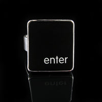 A silver ring featuring a black vertical rectangle with the lowercase letters 'enter', photographed on a reflective black surface.