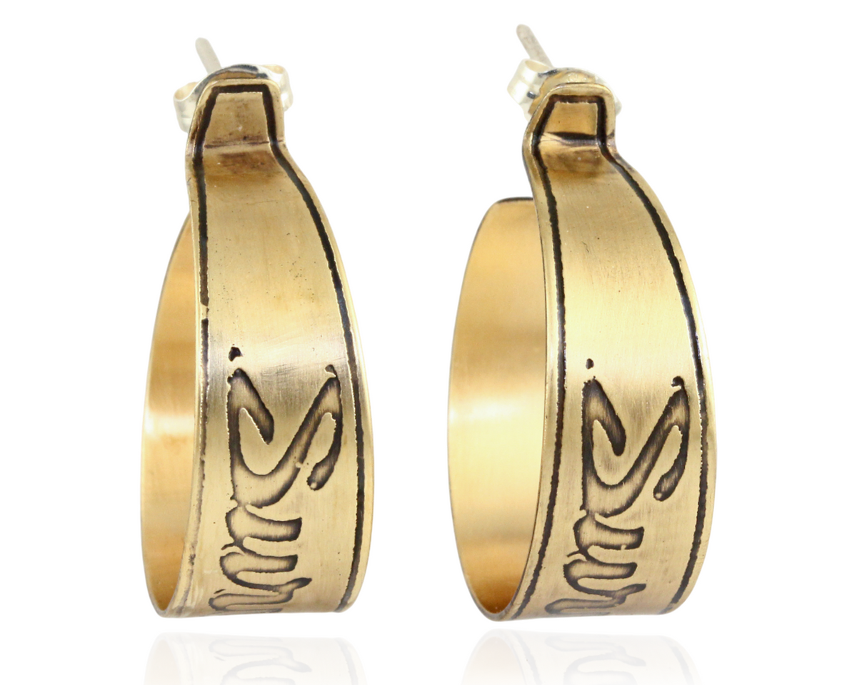Handmade nu-gold brass hoop earrings with engraved Survive design on a white background.