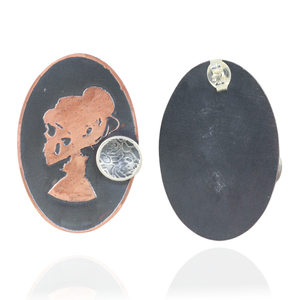 Oval pair of earrings with copper skull silhouette with a mini silver cup design on a white background.