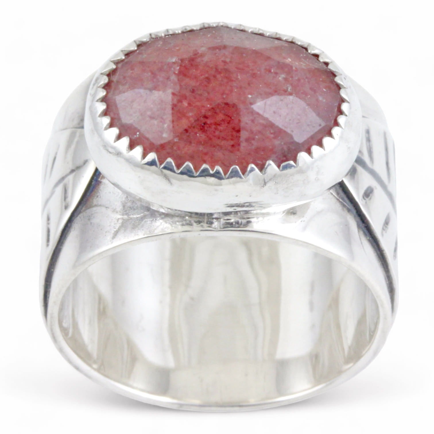 A sterling silver ring featuring a large, oval, faceted reddish-pink gemstone in a textured bezel setting, and a leaf on the ring band, shown on a plain white background.