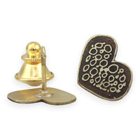 Heart-shaped metal pin with intricate designs on a white background