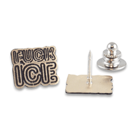 A brass pin with the words 'FUCK ICE' in raised black lettering on a distressed gold-toned background, shown alongside its silver metal pin backing  on a white background.