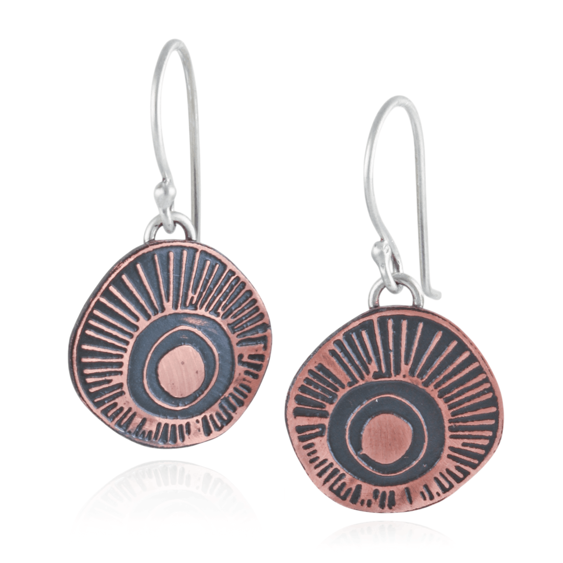 Copper and silver earrings with circular design on a white background