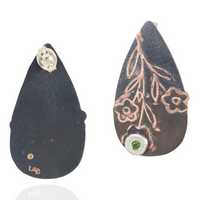 Teardrop-shaped earrings with floral designs and green peridot gemstones on a white background.