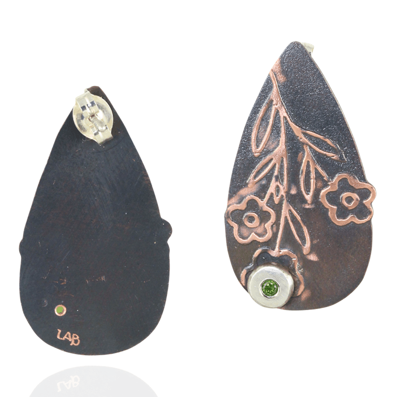 Teardrop-shaped earrings with floral designs and green peridot gemstones on a white background.