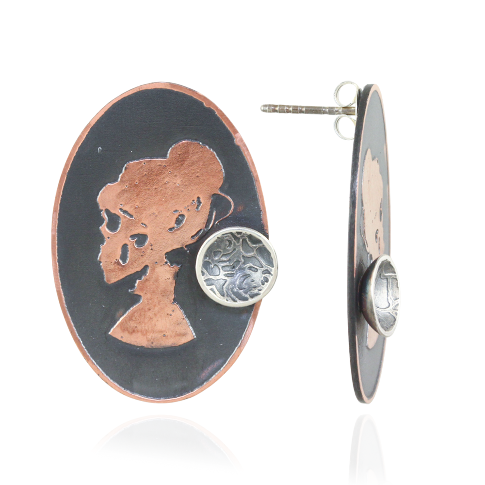 Oval pair of earrings with copper skull silhouette with a mini silver cup design  on a white background.