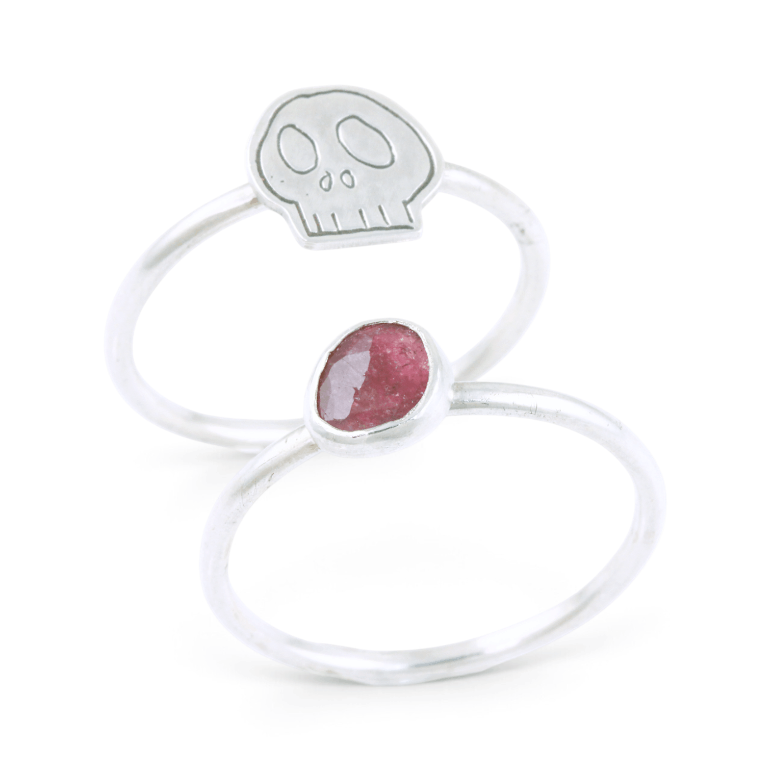 Two silvers ring together, featuring one with a pink gemstone and the other with an engraved skull motif, set against a clean white background.