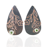 Teardrop-shaped earrings with floral designs and green peridot gemstones on a white background