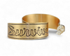 Handmade nu-gold brass hoop earrings with engraved 'Survive' design on a white background.