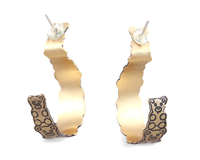 Gold hoop earrings with a interlocked teddy bear pattern on a white background.