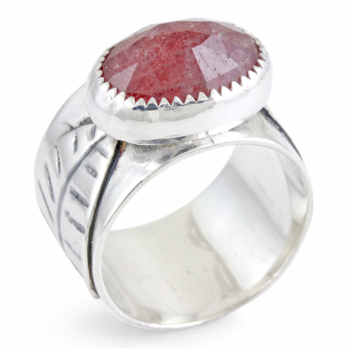 A sterling silver ring featuring a large, oval, faceted reddish-pink gemstone in a textured bezel setting, and a leaf on the ring band, shown on a plain white background.