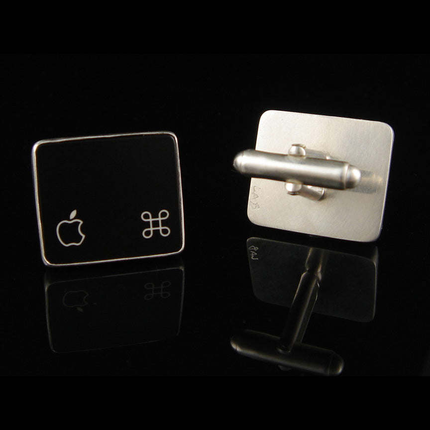 Two square cufflinks with Apple logo designs on a black background