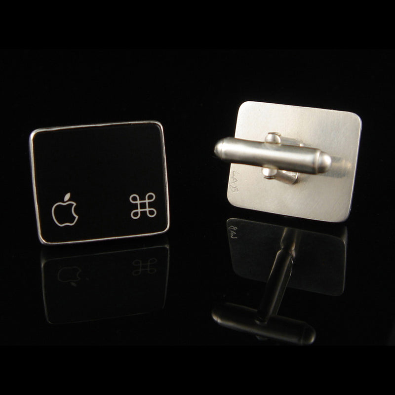Two square cufflinks with Apple logo designs on a black background