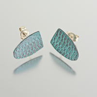 Two aqua-teal shield shaped earrings with a mod uniform snakeskin pattern on a light grey background.