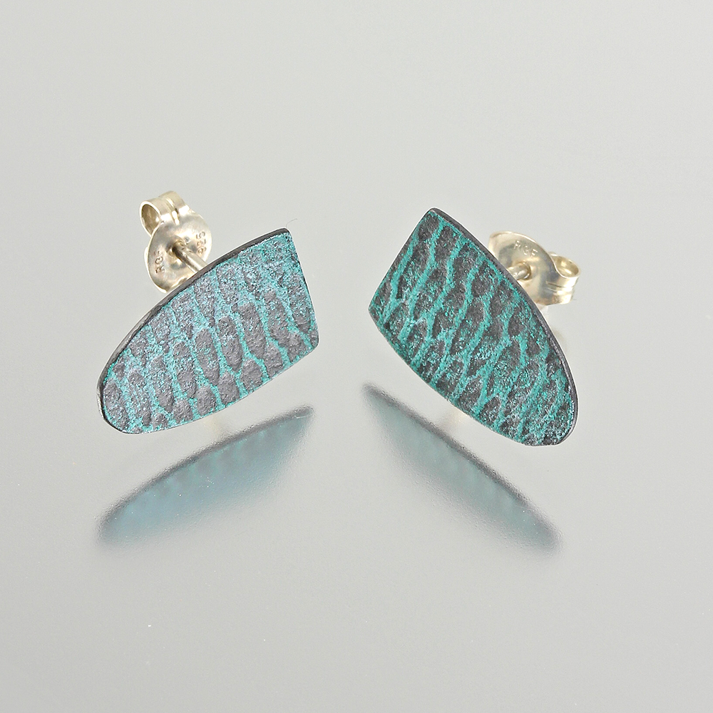 Two aqua-teal shield shaped earrings with a mod uniform snakeskin pattern on a light grey background.