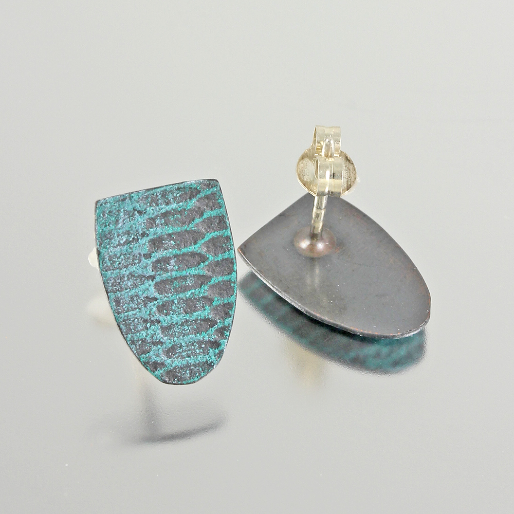 Two aqua-teal shield shaped earrings with a mod uniform snakeskin pattern on a light grey background.