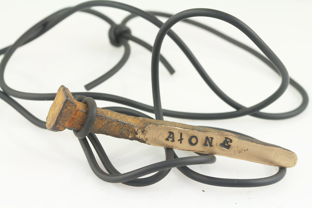 rePurposed brass nail with the word AtONE (with an upside down t) stamped on one side 