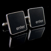 Black square cufflinks with 'enter' text on a reflective black surface