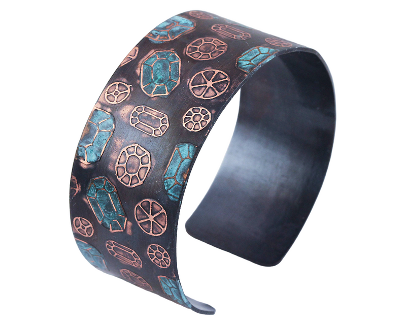 Copper cuff bracelet with gemstone pattern over the surface. Oxidized (darkened for contrast) then patinated (or coloring added) to some of the gemstones.
