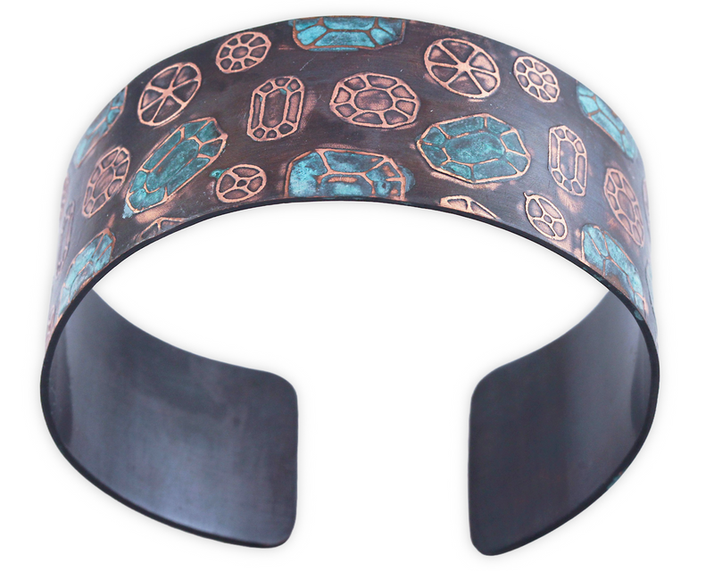 Copper cuff bracelet with gemstone pattern over the surface. Oxidized (darkened for contrast) then patinated (or coloring added) to some of the gemstones.