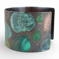 Metal cuff bracelet with green leaf pattern on a white background