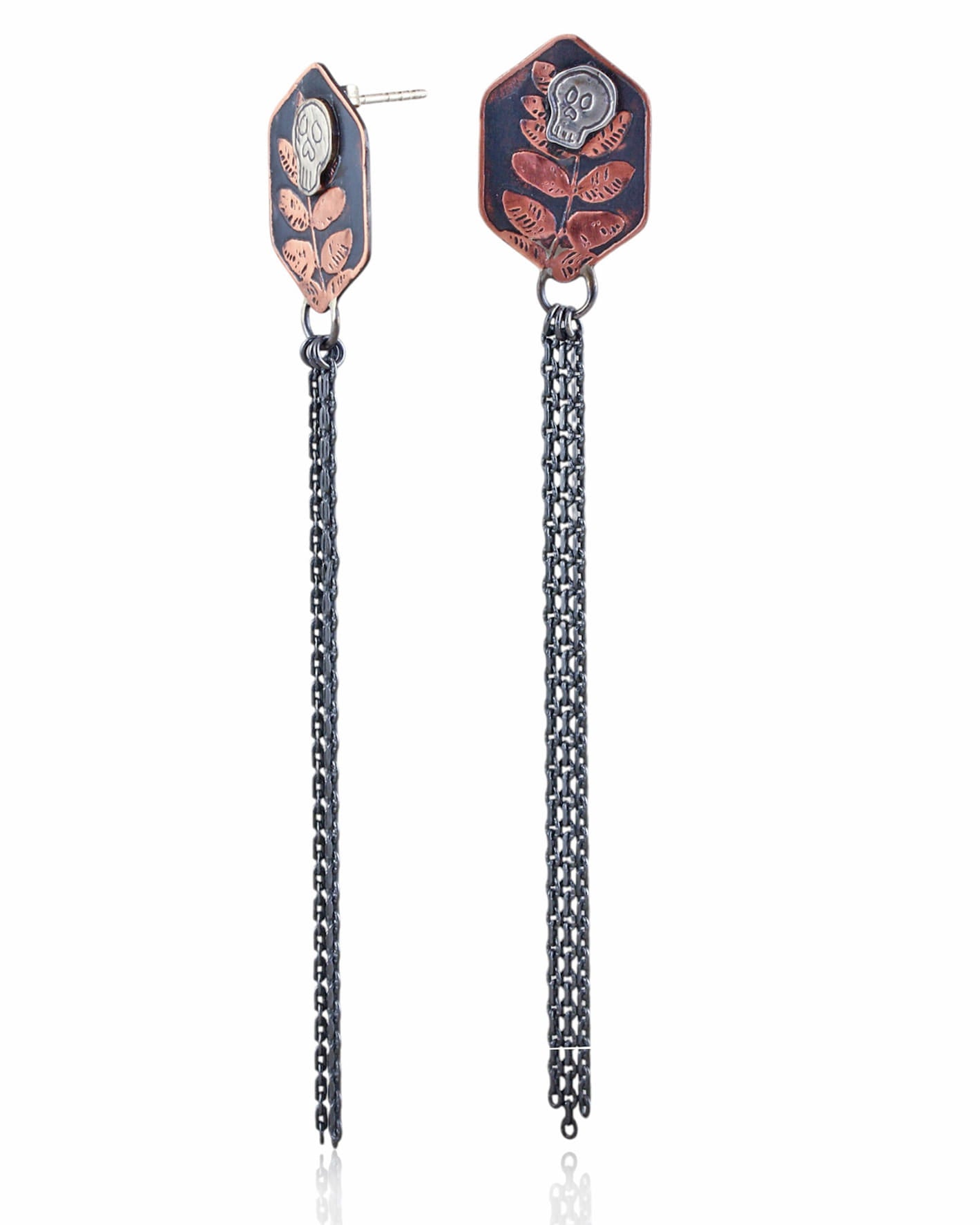 Pair of copper hexagon shaped earrings with silver skull designs and chain fringe details on a white background.