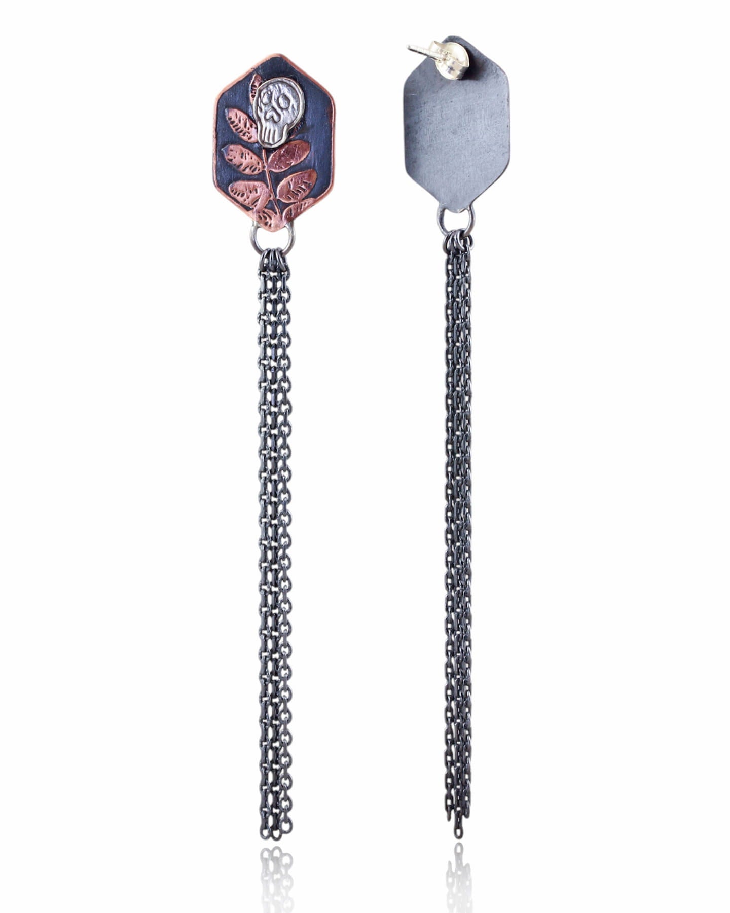 Pair of copper hexagon shaped earrings with silver skull designs and chain fringe details on a white background.