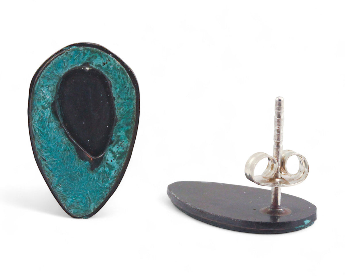 A pair of handmade copper teardrop-shaped stud earrings with a texture and a deep teal patina coating. Front and back view.