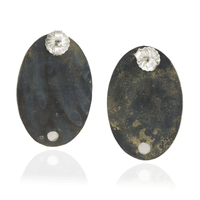 Pair of oval-shaped earrings with textured black surface and silver floral tops on a white background
