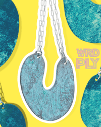 A blue earring with silver chains on a yellow and blue abstract background with 'WRD PLY' branding.