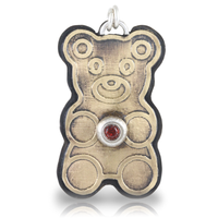 Gold teddy bear-shaped pendant with a red ruby gemstone on a white background