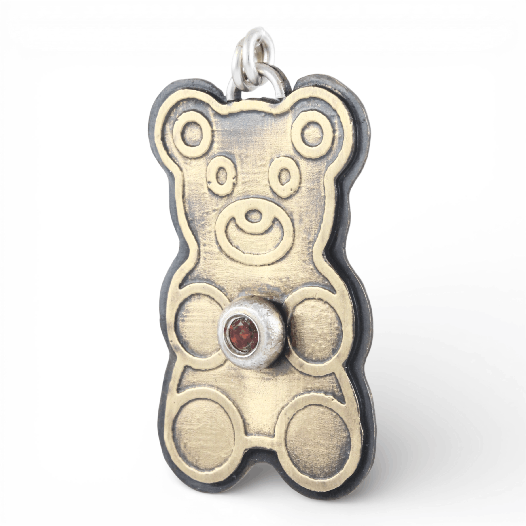 Gold teddy bear-shaped pendant with a red ruby gemstone on a white background