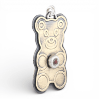 Gold teddy bear-shaped pendant with a red ruby gemstone on a white background