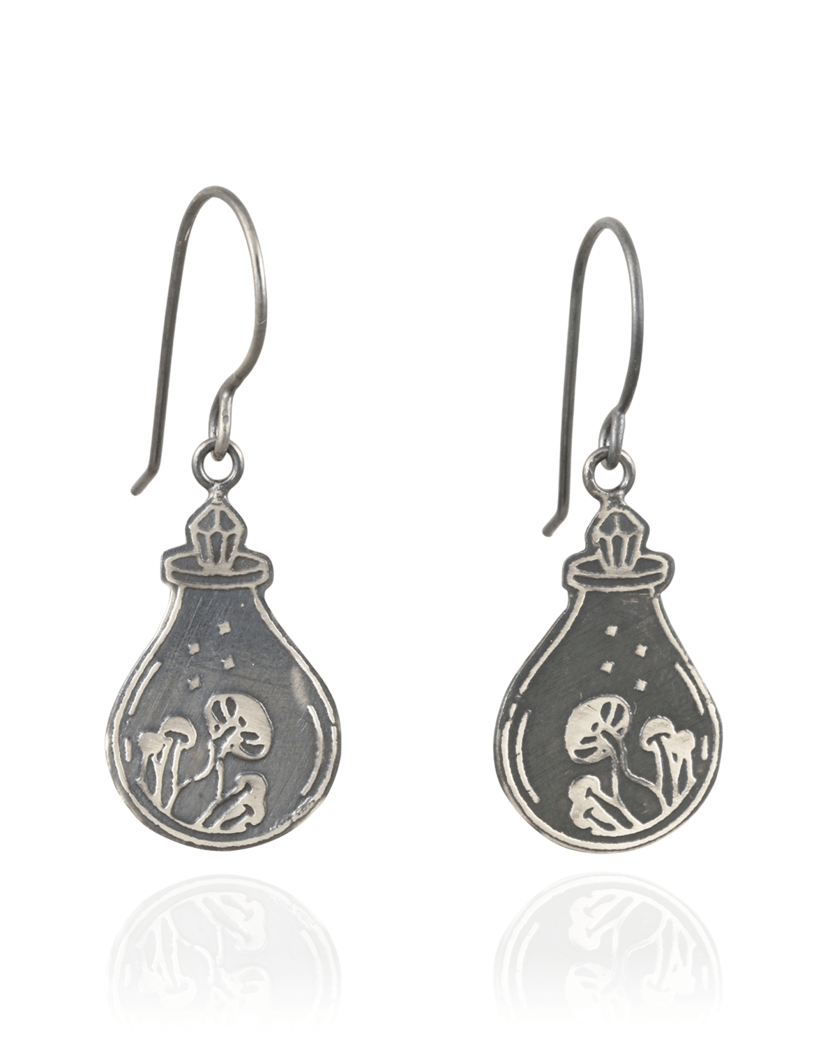 Silver earrings with a design of a potion bottle, with a crystal top, containing a mushrooms on a white background.