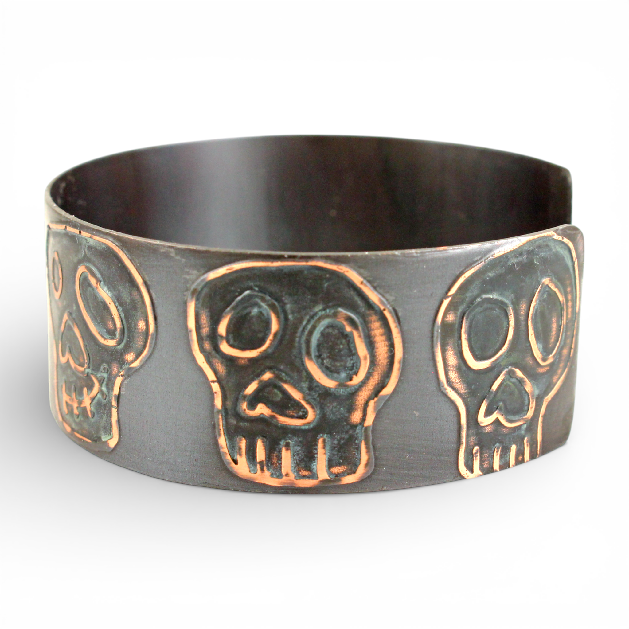 Copper cuff bracelet with intricate blue copper skull designs on a white background