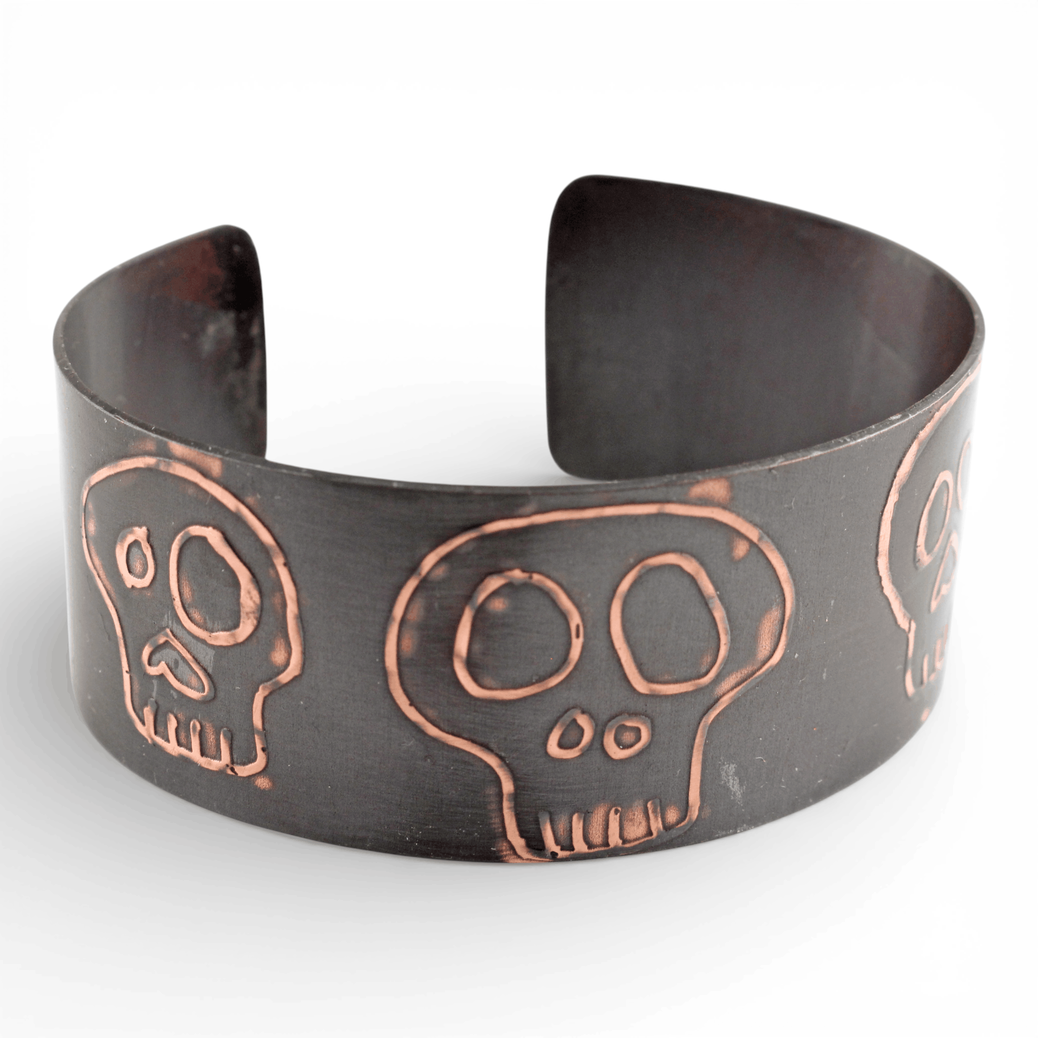 Black metal cuff bracelet with copper skull design on a white background