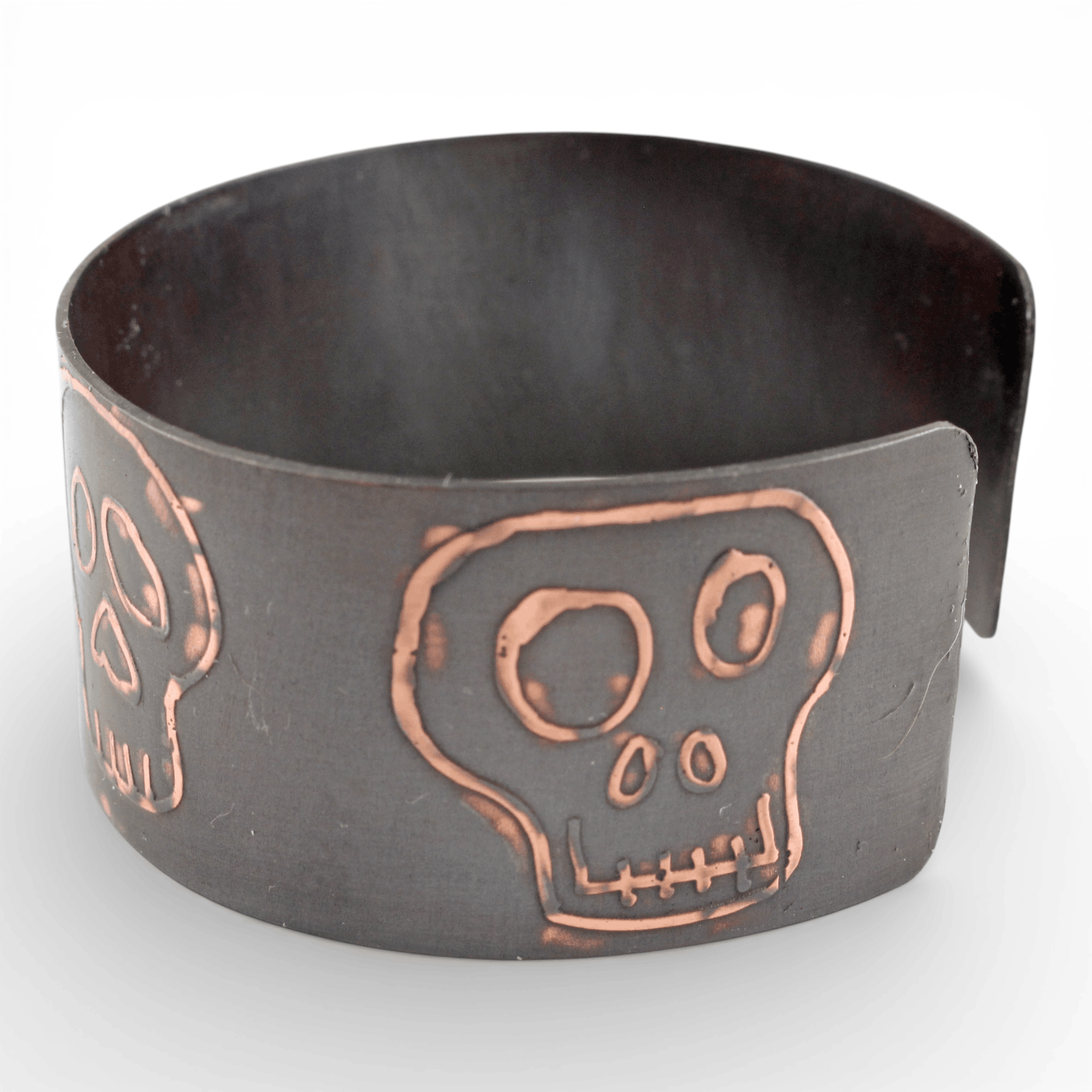 Black metal cuff bracelet with copper skull design on a white background