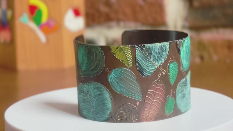360 of a handmade copper cuff bracelet that has a verdigris green patination leaf pattern on a rotating white surface.  Bracelet by Lauren Anabela of Creative Dexterity