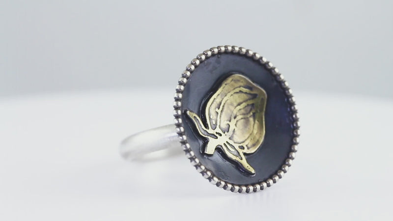 Video of sterling silver domed ring with a brass flower bud image in the center.