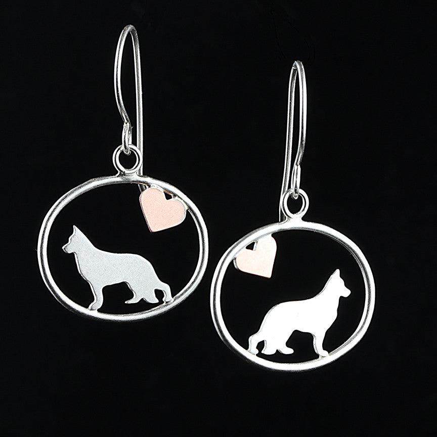 Sterling silver German Shepherd dangle earrings with a small copper heart inside oval frames, matte finish on black background.